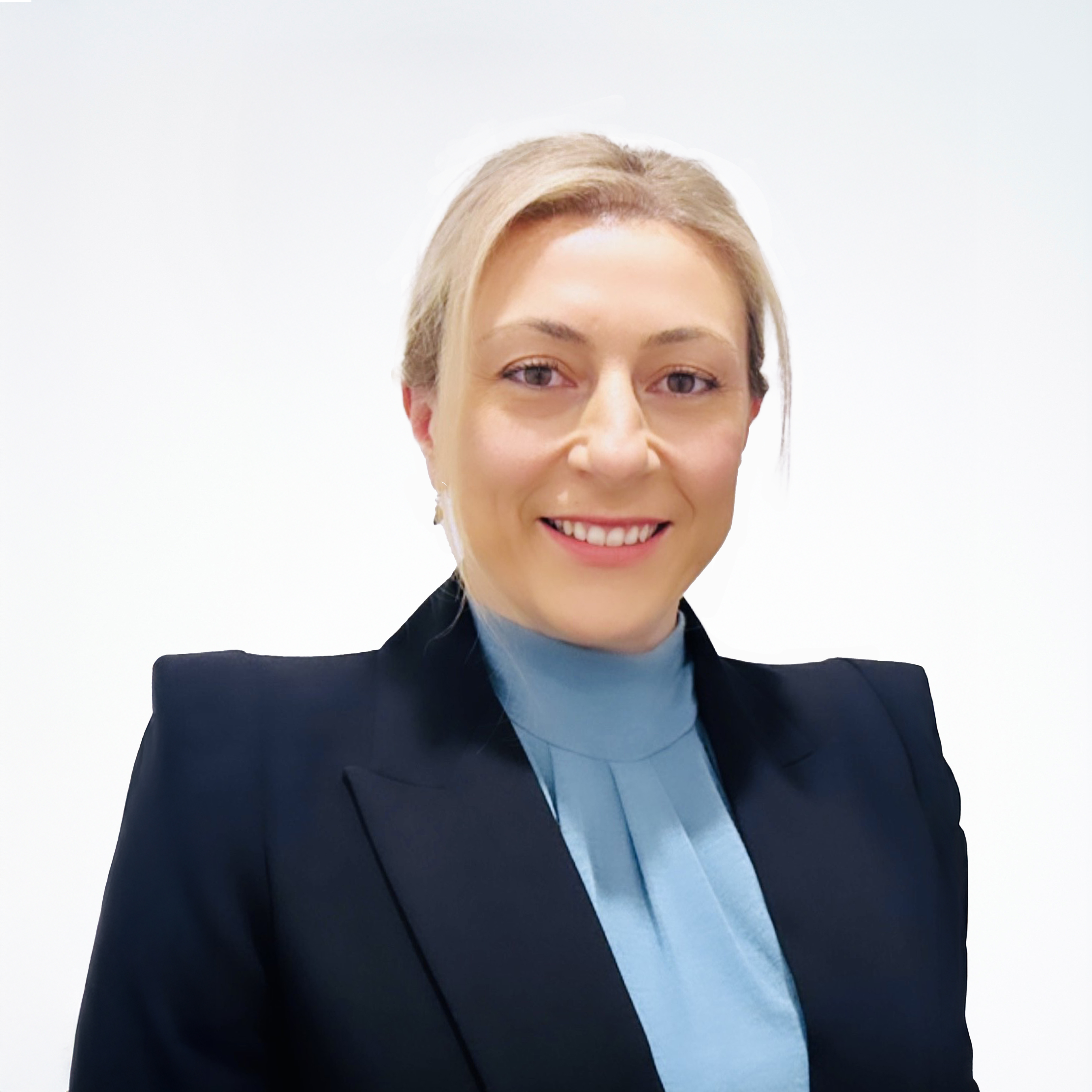 Headshot of Human Resources General Manager Eylem Shipley, smiling and wearing a dark blazer over a light blue high-neck blouse.
