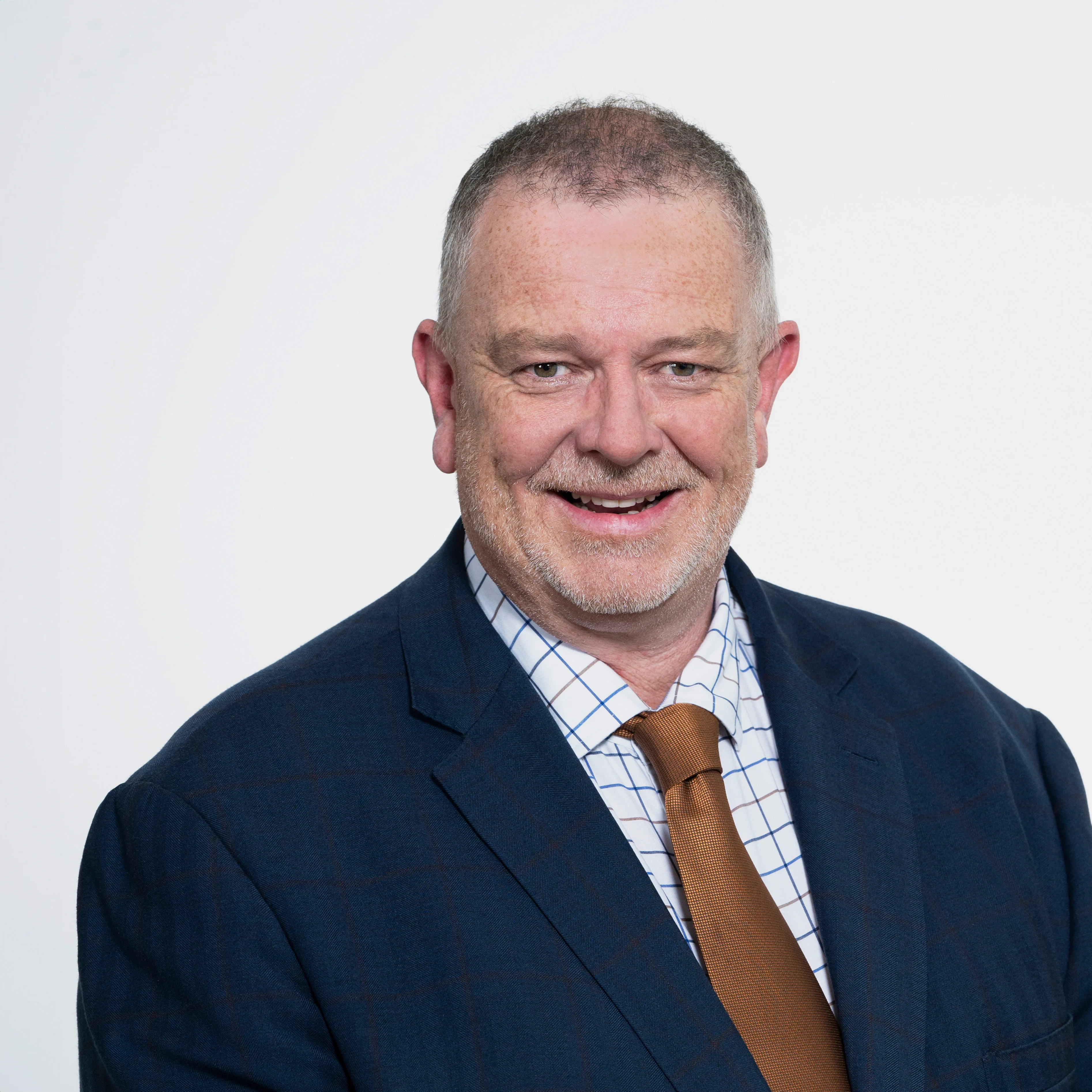 Headshot of General Manager Murray Wilton, smiling and wearing a dark suit and brown tie with a checkered shirt.