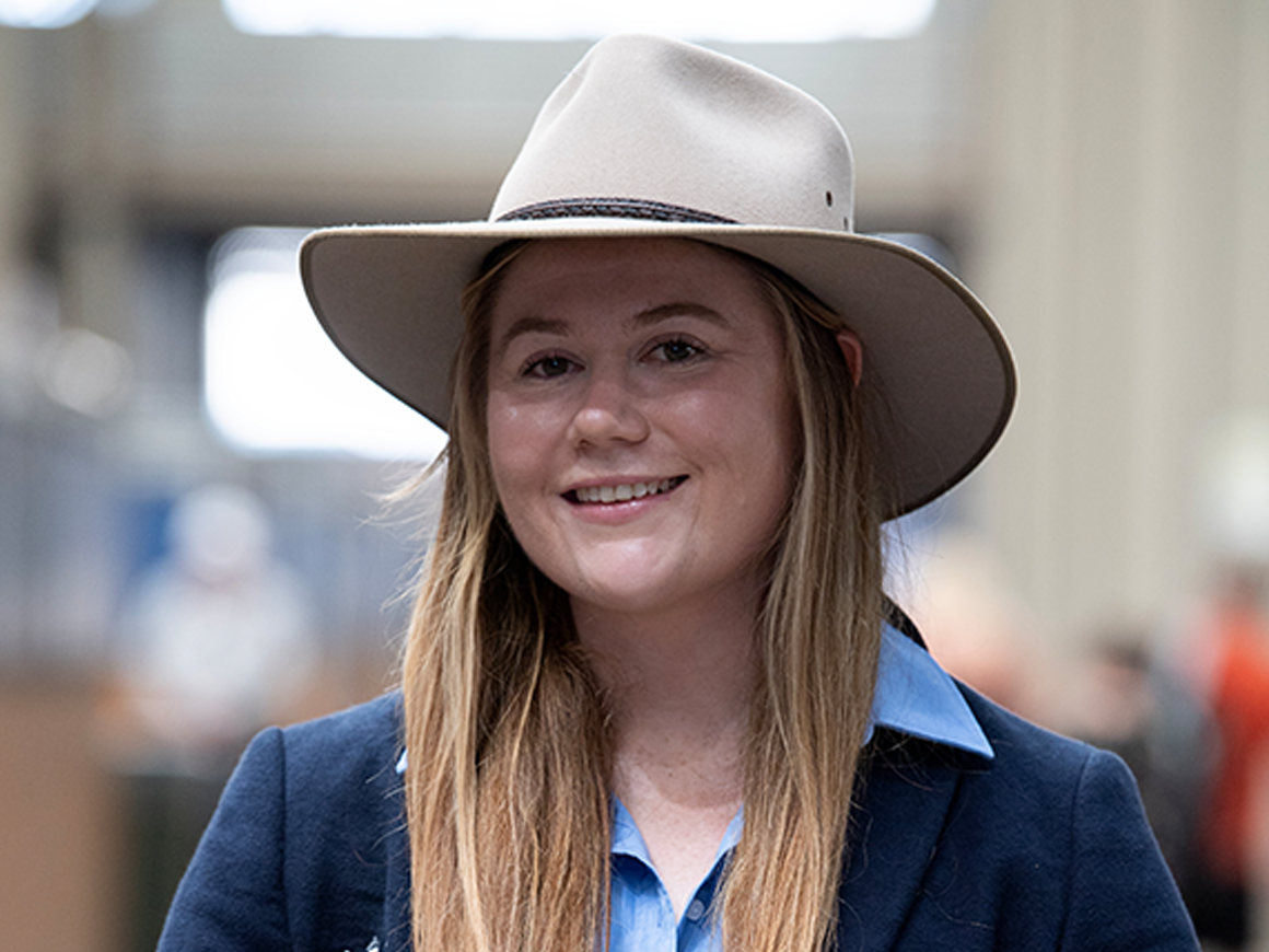 Headshot of Kelsey Noble, a woman with long blonde hair, smiling in a suit and hat, winner of the 2023 RAS Rural Achiever Award.