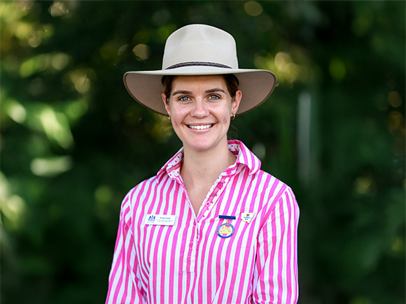 Headshot of  2025 finalist Eloise Haigh, a woman with brown hair, wearing small hoop earrings and a wide-brimmed hat.