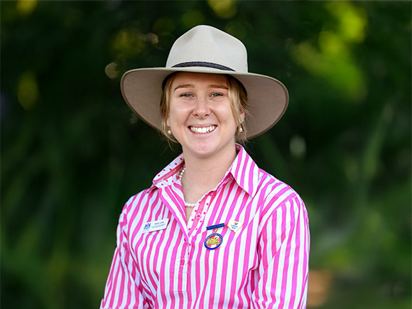 Headshot of 2025 finalist Emily Lucas, a woman with blonde hair, smiling, wearing pearl earrings and a wide-brimmed hat.